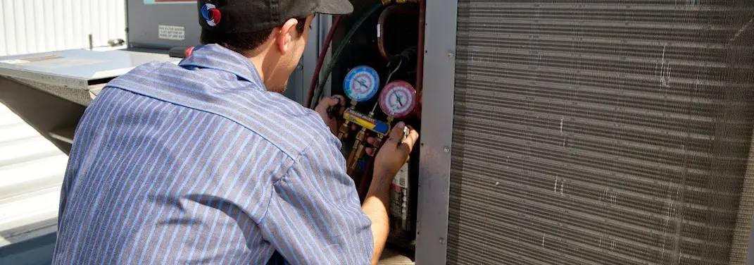 HVAC technician servicing a condenser unit in Frankfort